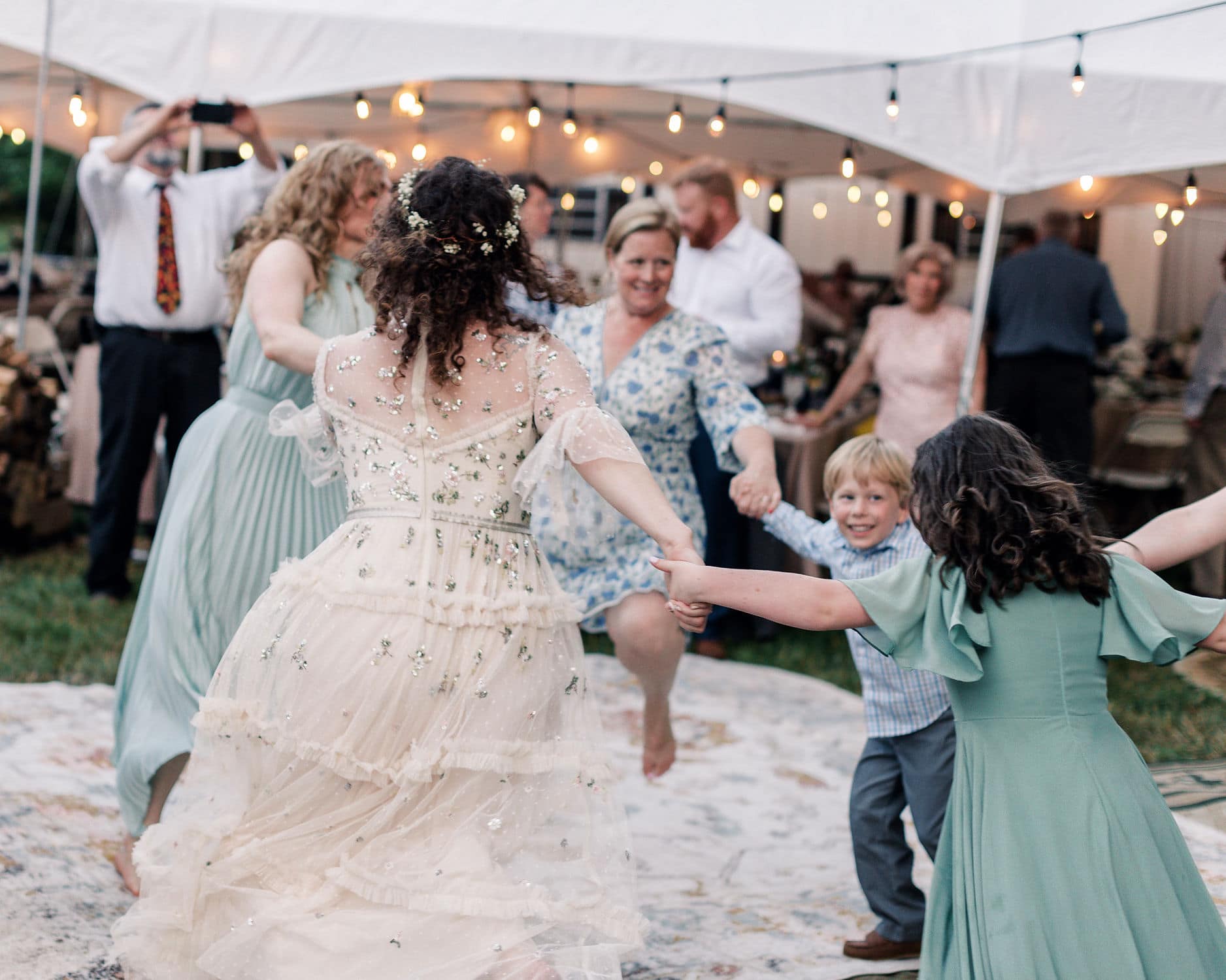 a twlight wedding party under a white tent and twinkle lights