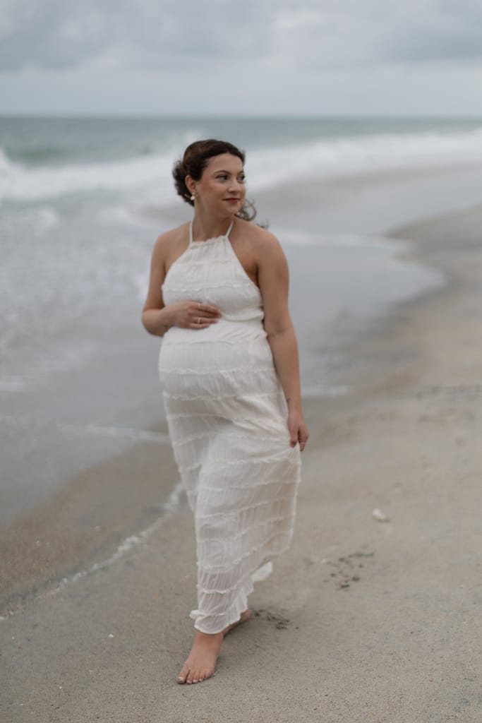 Woman walking barefoot along the edge of the ocean in Emerald Isle, soft waves curling at her feet.