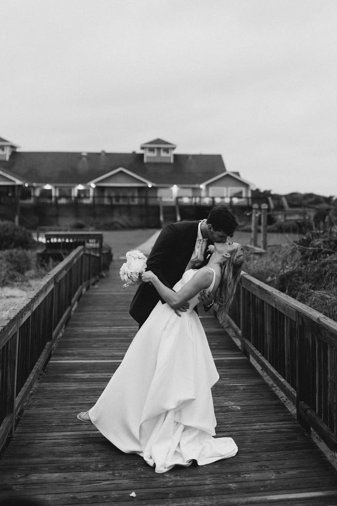 A bride and groom dip for a kiss outside their wedding venue in Atlantic Beach, NC