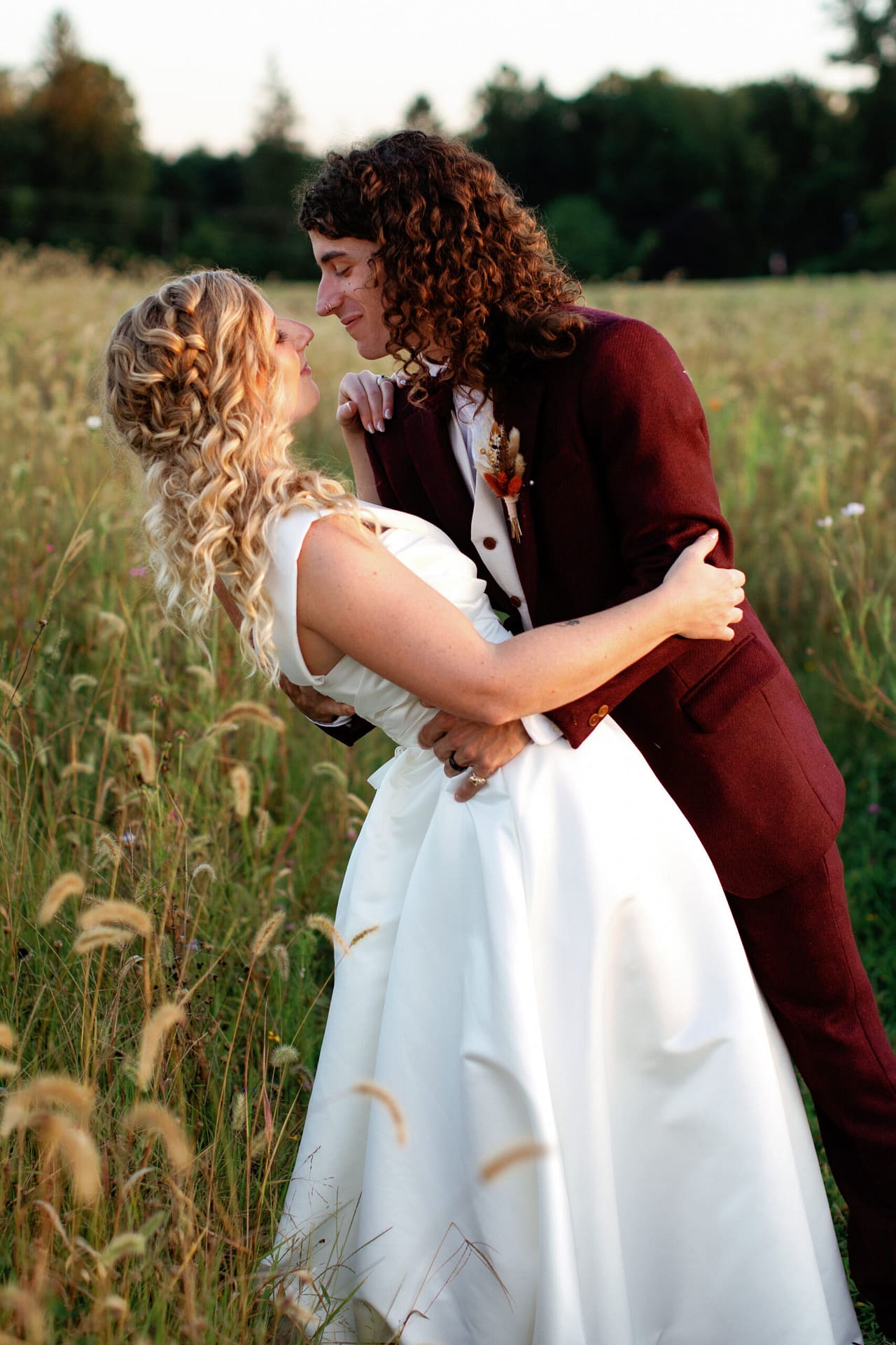 A bride and groom dip for a kiss during golden hour. 