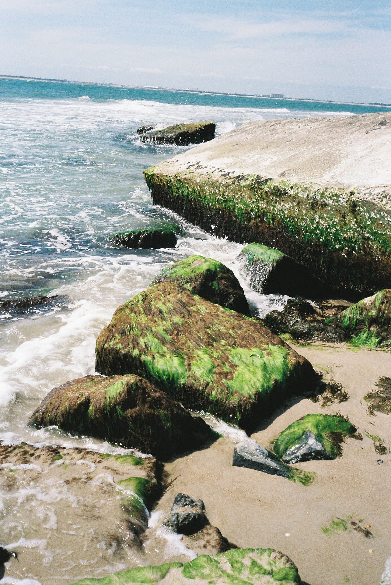Waves crashing against rocky shoreline on the Crystal Coast, showing the raw beauty of the North Carolina coast.