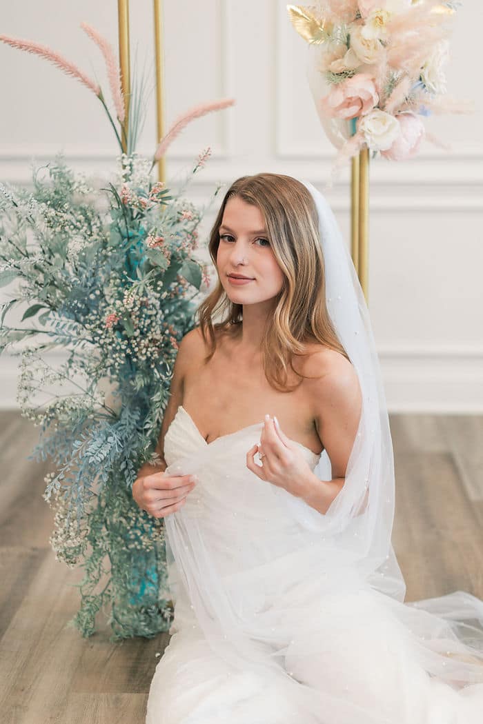 studio bridal portraits with a pearl inlayed wedding veil and a white bridal jumpsuit