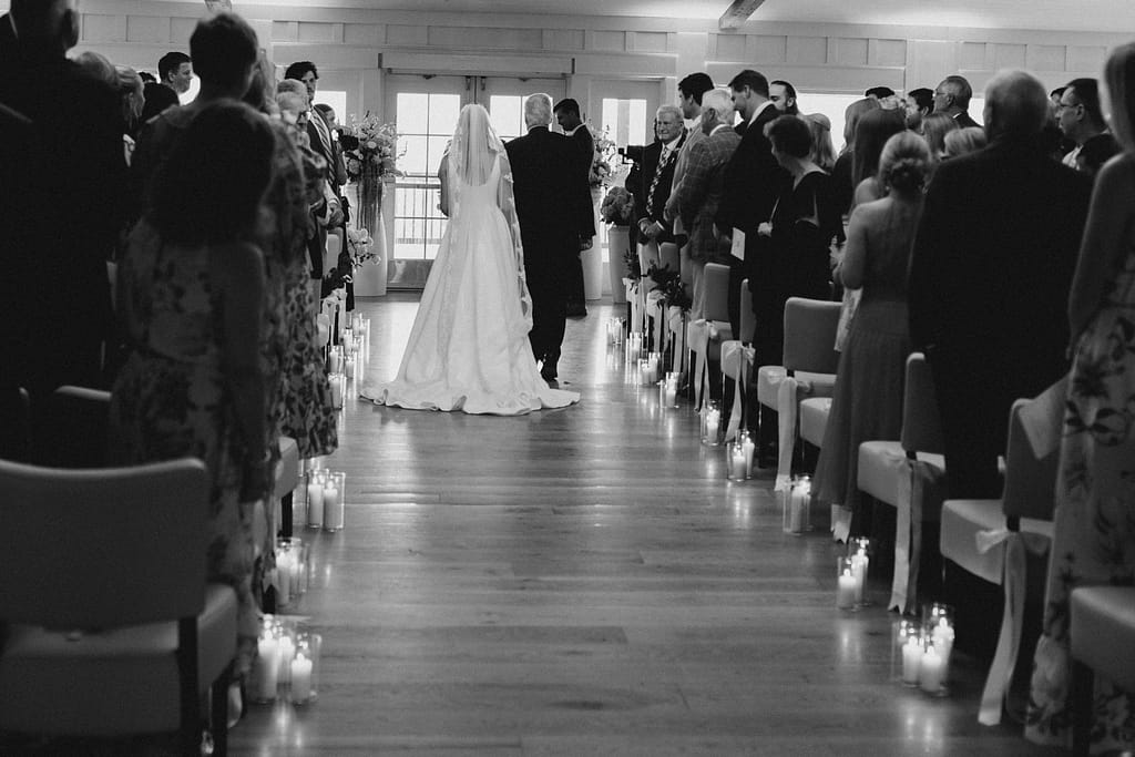 Bride walking down candlelit aisle during ceremony at The Dunes Club, Atlantic Beach, NC, black and white.